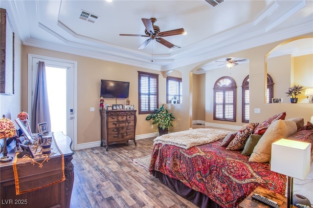 bedroom featuring ceiling fan, hardwood / wood-style floors, a tray ceiling, and ornamental molding