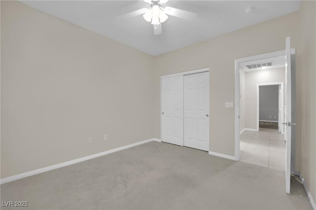 unfurnished bedroom with ceiling fan, light colored carpet, and a closet