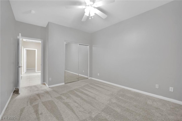 unfurnished bedroom with ceiling fan, light carpet, and a closet