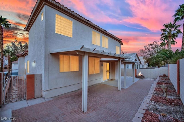 back house at dusk with a patio area