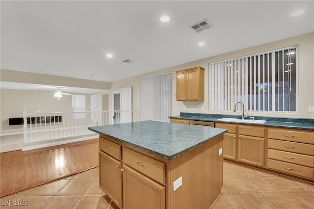 kitchen with ceiling fan, dishwasher, sink, light tile patterned flooring, and a kitchen island