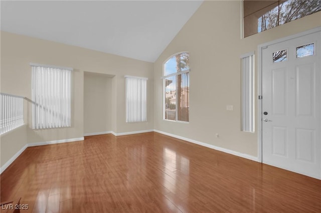 foyer featuring wood-type flooring and high vaulted ceiling