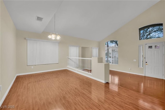 spare room featuring hardwood / wood-style flooring, high vaulted ceiling, and a chandelier