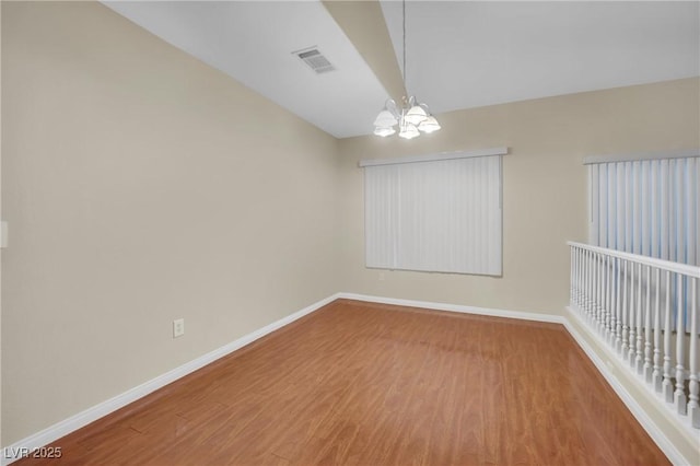 unfurnished room featuring hardwood / wood-style floors and a chandelier