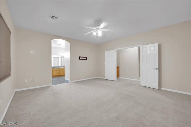 unfurnished bedroom with light carpet, ensuite bath, and ceiling fan