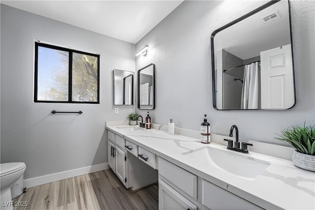 bathroom with hardwood / wood-style flooring, vanity, toilet, and walk in shower