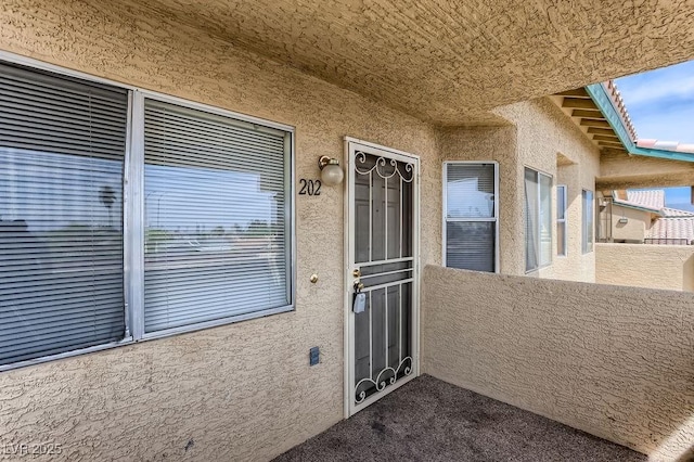 view of exterior entry with a balcony