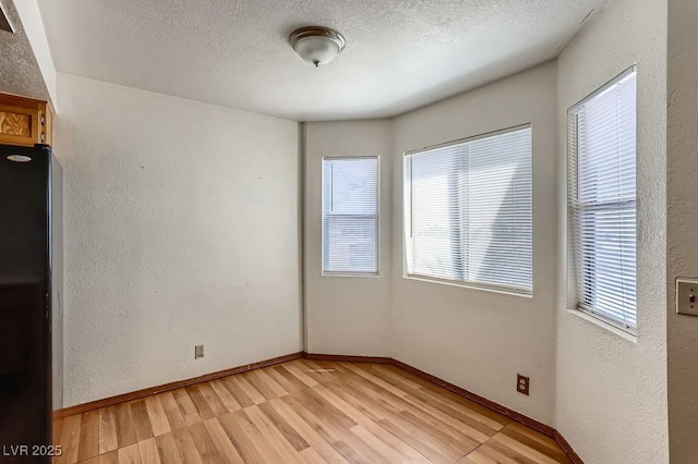 unfurnished room with a textured ceiling and light hardwood / wood-style flooring