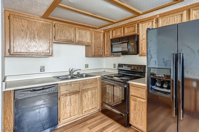 kitchen with black appliances, light wood-type flooring, and sink