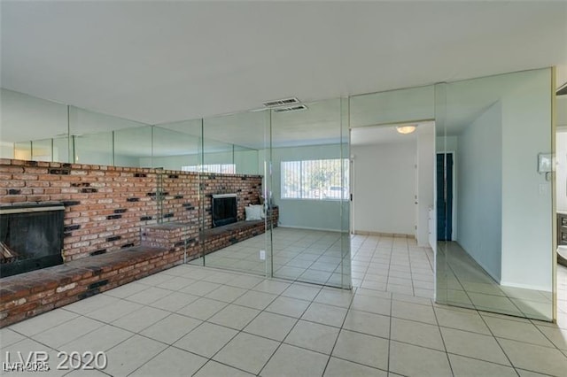 unfurnished living room with a fireplace and light tile patterned floors