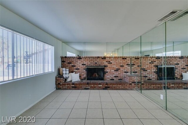 unfurnished living room with a wealth of natural light, a fireplace, and tile patterned flooring