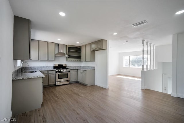 kitchen featuring gray cabinetry, stainless steel range, wall chimney exhaust hood, sink, and light hardwood / wood-style flooring