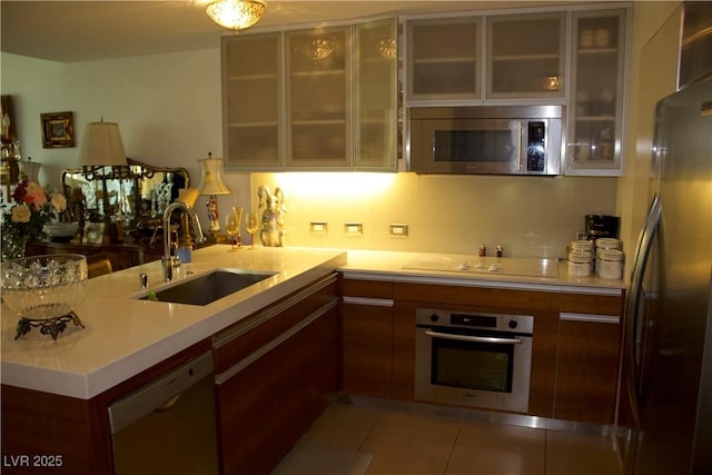 kitchen with light tile patterned flooring, sink, kitchen peninsula, and stainless steel appliances