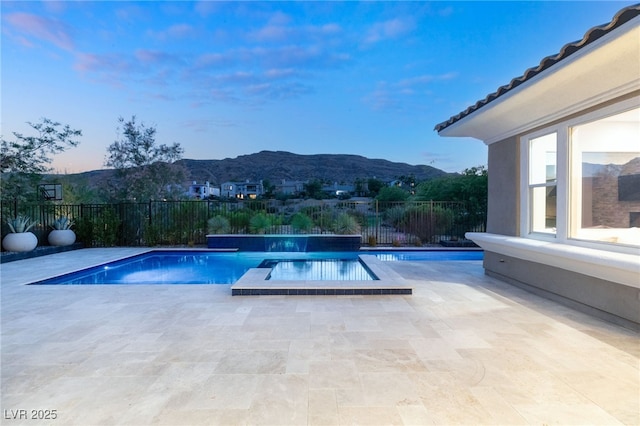 pool at dusk featuring a mountain view and a patio