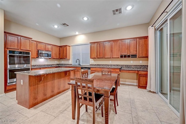 kitchen with a kitchen breakfast bar, light stone countertops, a kitchen island, and stainless steel appliances