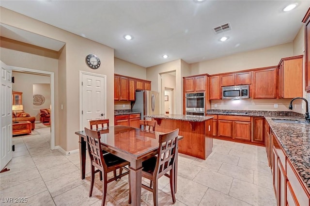 kitchen featuring sink, a center island, light tile patterned flooring, and appliances with stainless steel finishes