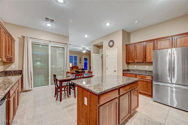 kitchen featuring a kitchen island, light stone counters, stainless steel appliances, and light tile patterned flooring