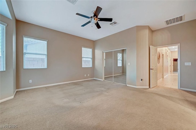 unfurnished bedroom featuring a closet, light colored carpet, and ceiling fan