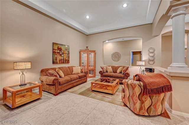 living room featuring a raised ceiling, a high ceiling, and decorative columns