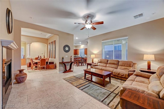 tiled living room featuring ornate columns and ceiling fan