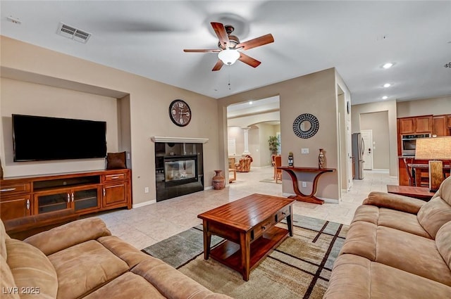 living room with ceiling fan, light tile patterned flooring, ornate columns, and a fireplace