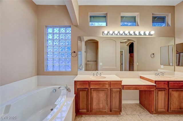 bathroom with tile patterned flooring, a relaxing tiled tub, and vanity