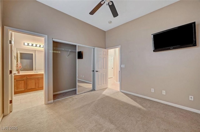 unfurnished bedroom featuring ceiling fan, a closet, light colored carpet, and ensuite bathroom