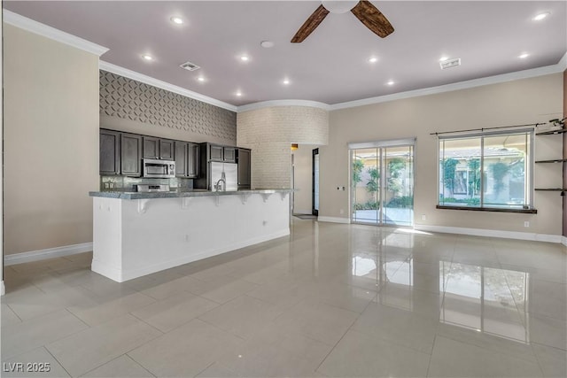 kitchen featuring a kitchen bar, light stone countertops, ornamental molding, stainless steel appliances, and ceiling fan