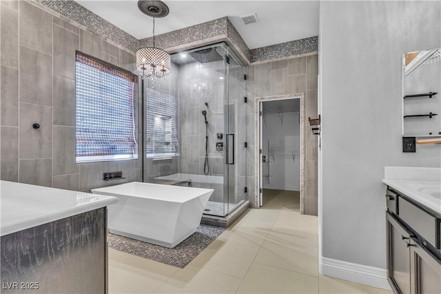 bathroom with vanity, plus walk in shower, an inviting chandelier, tile patterned floors, and tile walls