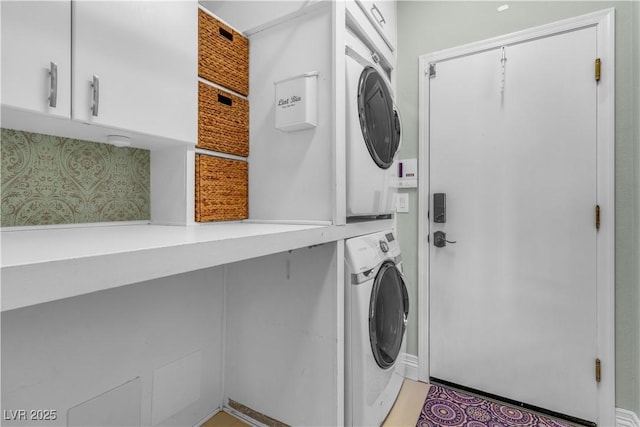 laundry area with cabinets and stacked washer and clothes dryer