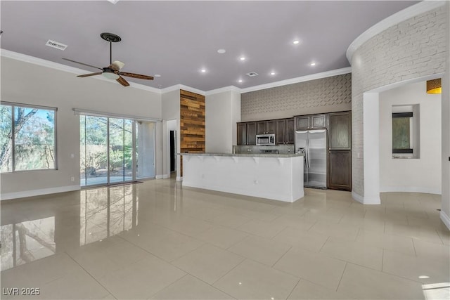 kitchen featuring a center island, crown molding, ceiling fan, light stone countertops, and stainless steel appliances