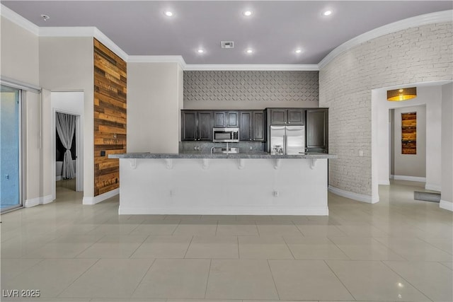 kitchen with a kitchen bar, a large island, crown molding, and appliances with stainless steel finishes