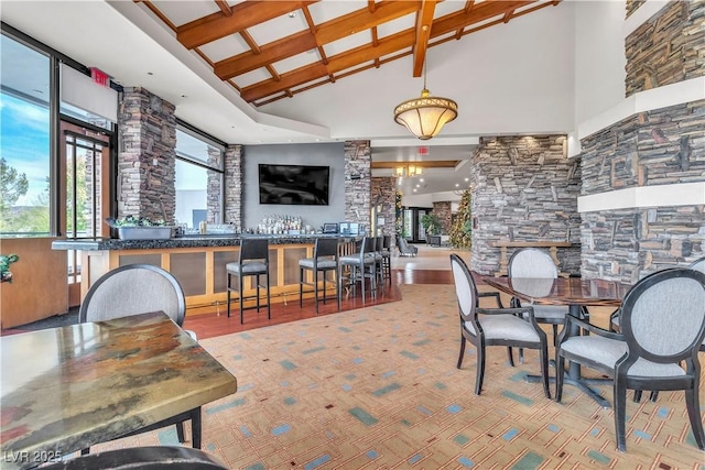 dining area with beam ceiling, a towering ceiling, indoor bar, and coffered ceiling