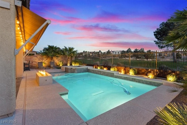 pool at dusk with a fire pit and an in ground hot tub