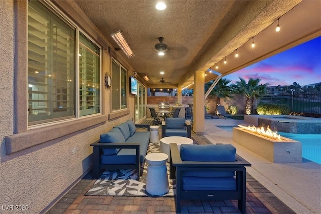 patio terrace at dusk featuring a swimming pool with hot tub, an outdoor living space with a fire pit, and ceiling fan