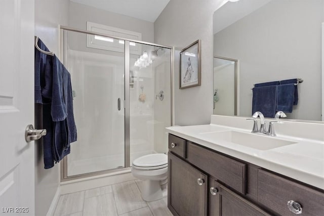 bathroom with a shower with door, vanity, and toilet