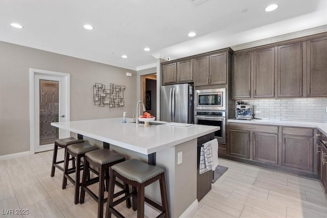 kitchen featuring appliances with stainless steel finishes, tasteful backsplash, sink, a center island with sink, and a breakfast bar area