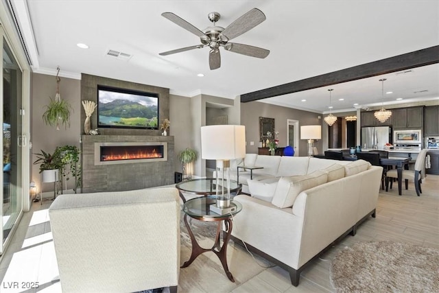 living room featuring ceiling fan, a fireplace, and crown molding