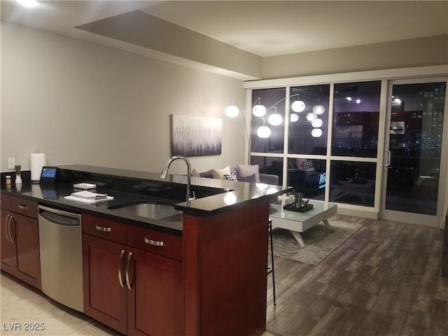 kitchen featuring a kitchen breakfast bar, light wood-type flooring, stainless steel dishwasher, and sink