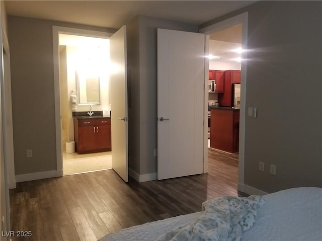 bedroom with hardwood / wood-style floors, sink, and connected bathroom