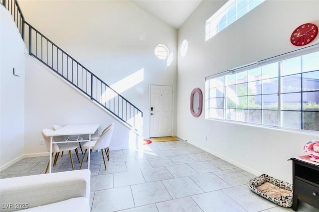 tiled foyer entrance featuring a towering ceiling and a healthy amount of sunlight