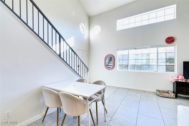 dining space with a towering ceiling and light tile patterned flooring