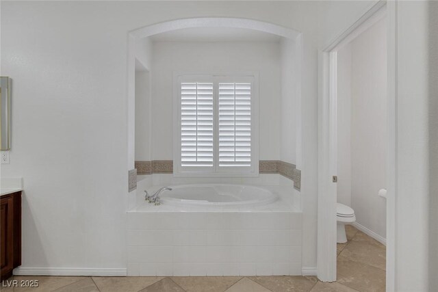 bathroom featuring tile patterned floors, vanity, a relaxing tiled tub, and toilet