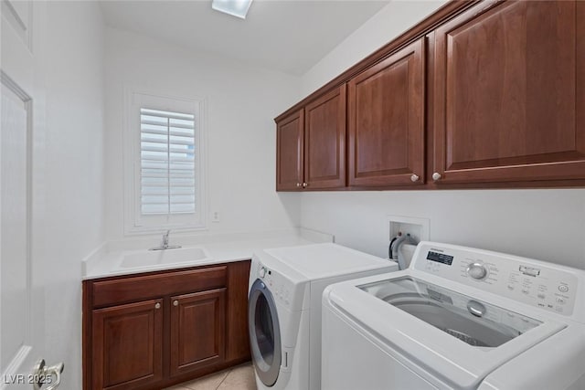 clothes washing area with washer and dryer, sink, light tile patterned flooring, and cabinets