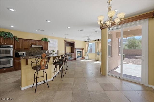 kitchen with pendant lighting, decorative backsplash, dark stone countertops, a breakfast bar area, and stainless steel appliances