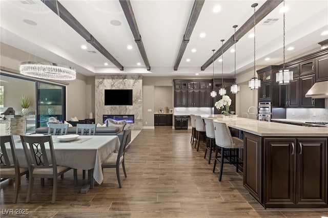 dining space with beamed ceiling, a fireplace, and an inviting chandelier