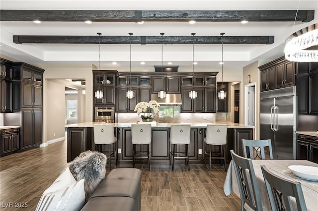 kitchen with hanging light fixtures, a kitchen bar, dark brown cabinets, a kitchen island, and appliances with stainless steel finishes