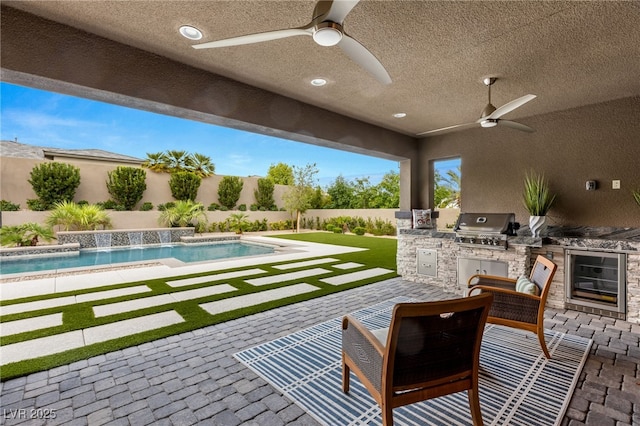 view of patio / terrace featuring pool water feature, an outdoor kitchen, ceiling fan, and area for grilling