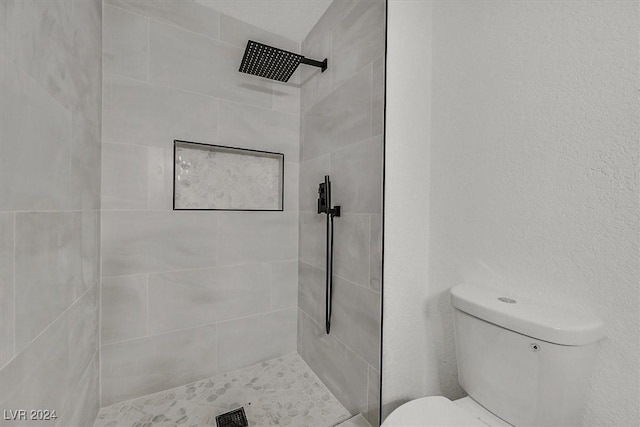 bathroom featuring a tile shower and toilet