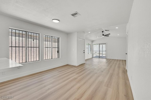 unfurnished living room with ceiling fan, light wood-type flooring, and lofted ceiling